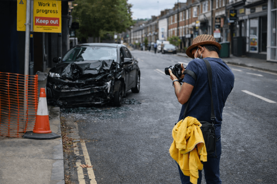 A man taking a photograph of a car crash