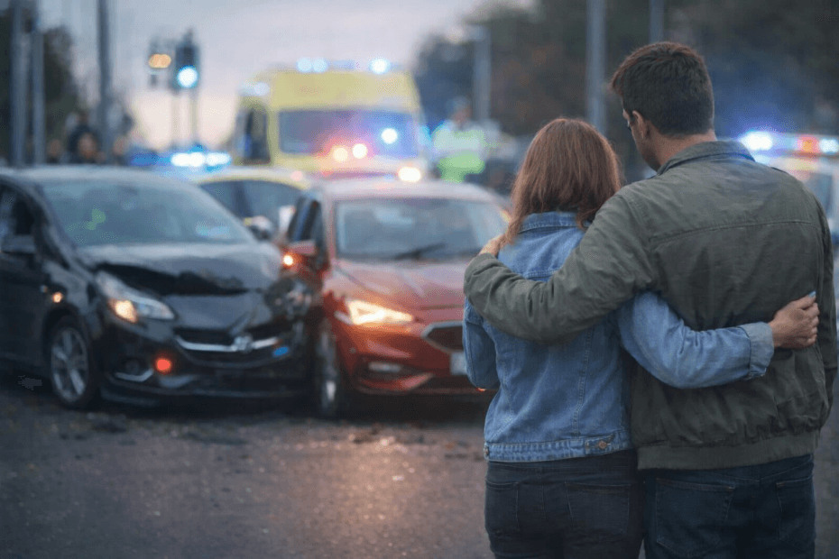 A man and woman looking at the scene of a car accident.